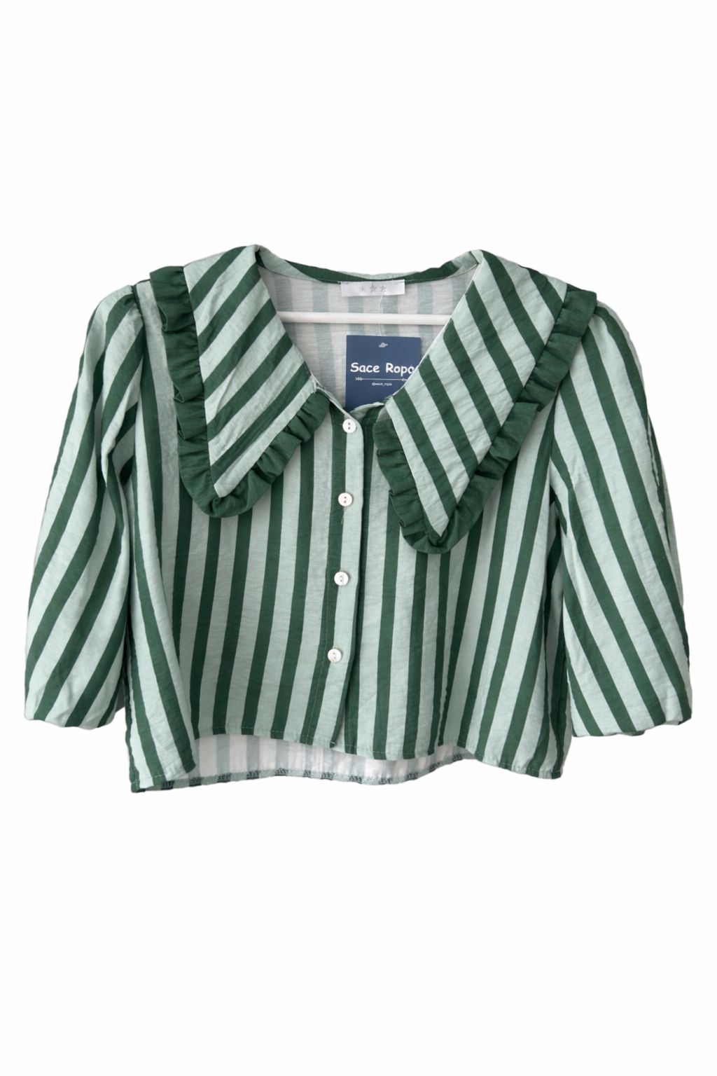 Blusa corta de mujer a rayas con cuello maxi en pico ribeteado con un volante pequeño y manga al codo abullonada. Diseño ligero con botones ideal para looks elegantes y casuales.