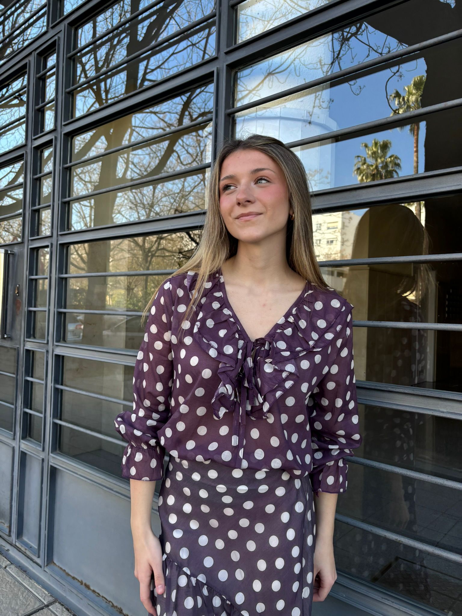 Blusa semitransparente con estampado de lunares y escote con volantes y lazada. Manga larga con puño fruncido, diseño femenino y ligero ideal para looks elegantes.