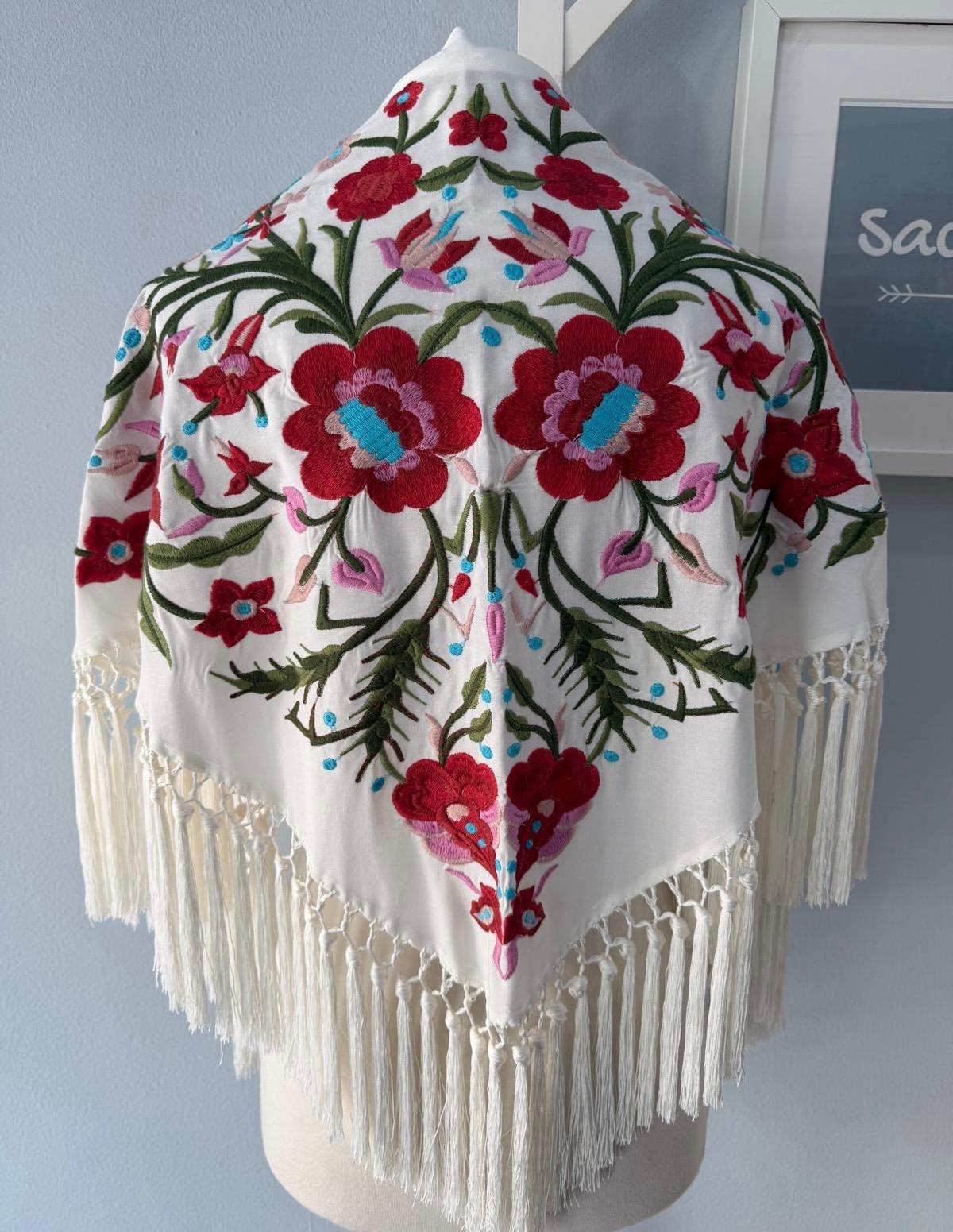 Mantón bordado de Cantillana, con flores de gran detalle y un acabado tradicional espectacular. Con flecos que le dan movimiento y un estilo único, acabado en pico.