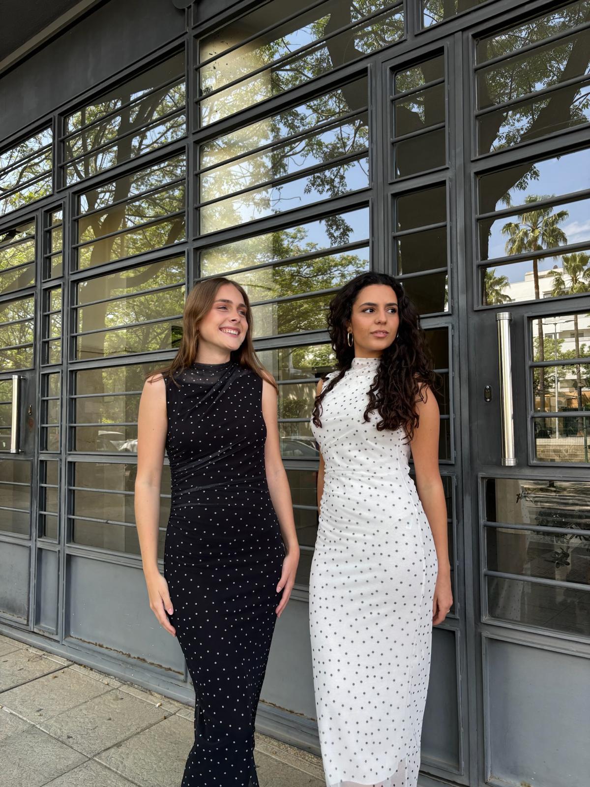 Vestido midi de lunares pequeños ajustado en tejido elástico con elegante cuello alto y sutil drapeado que estiliza la silueta. Diseño en negro con delicado estampado de lunares, ideal para un look sofisticado tanto de día como de noche. Ideal para el día de Pescaito.