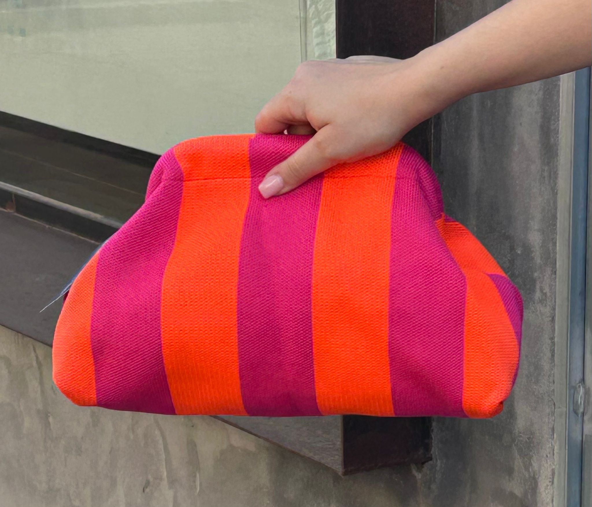 Bolso tipo clutch de punto de algodón, de rayas haciendo contraste los colores. Ligero, con una cadena dorada dentro que la puedes sacar para colgártelo. Perfecto para dar vida al look